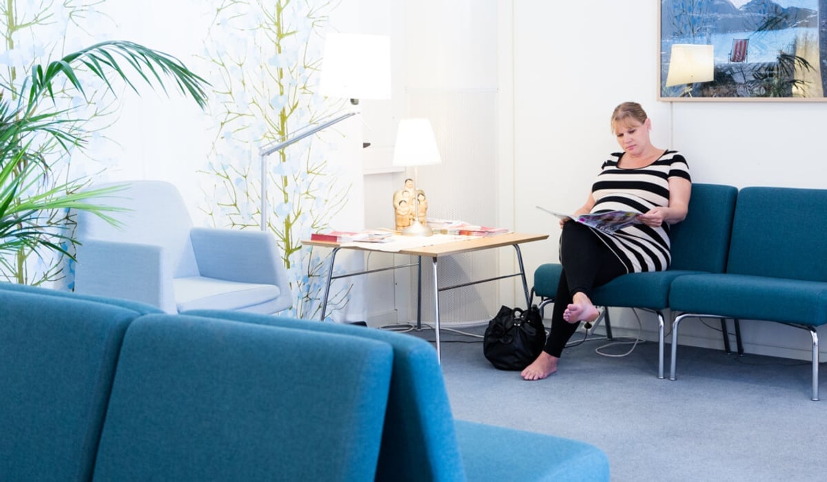 En kvinna sitter på en blå soffa i ett vardagsrum.