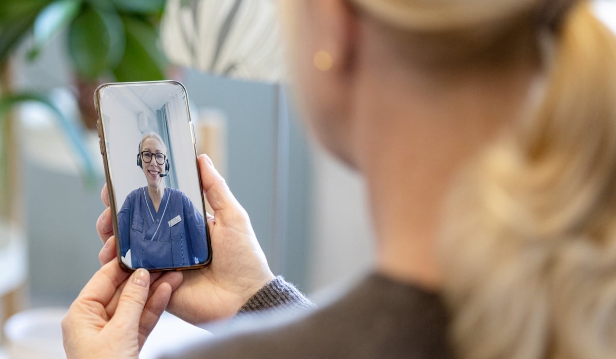 En kvinna håller upp sin mobiltelefon.