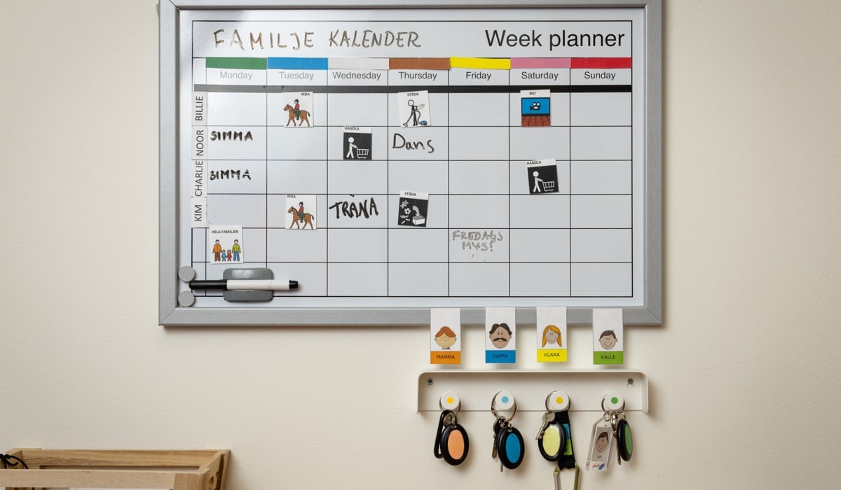 En vit tavla monterad på en vägg med en kalender på.
