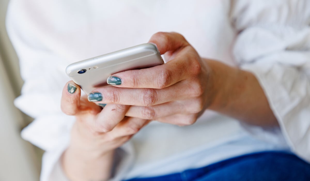 En närbild på en person som håller i en mobiltelefon.