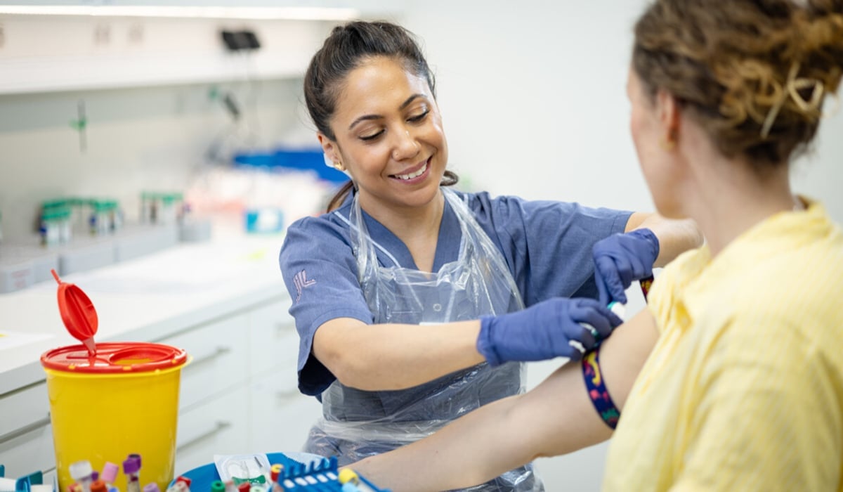 Sjuksköterska förbereder provtagning på kvinnlig patient.