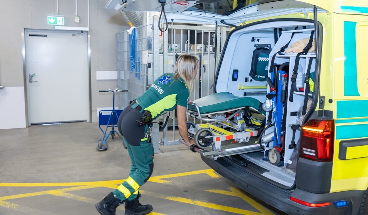 En kvinna i gröngul uniform står bredvid en skåpbil.