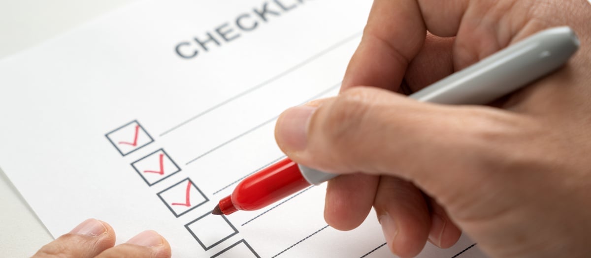 En person som fyller i en checklista med en penna.