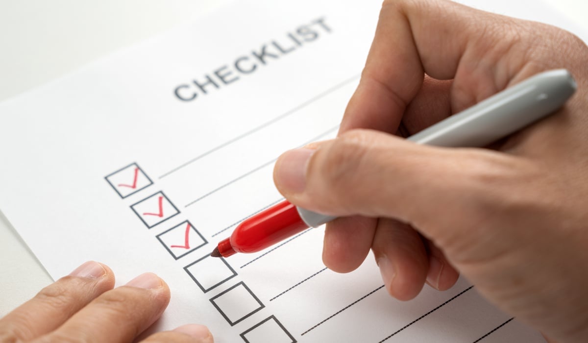 En person som fyller i en checklista med en penna.