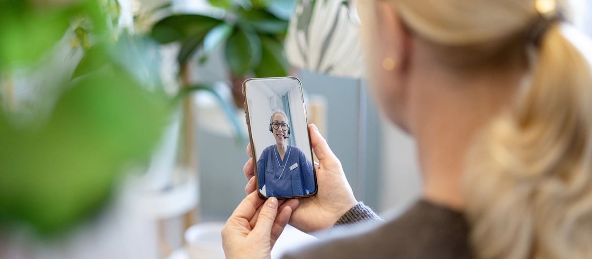 En kvinna håller upp sin mobiltelefon.